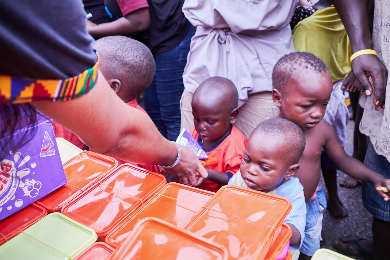 Young children receiving essential supplies from volunteers during a distribution event.